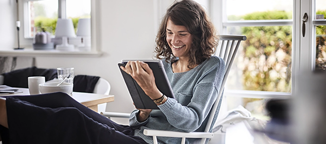 Relaxed young woman sitting at table using tablet