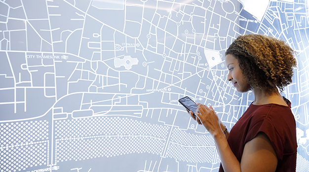 Woman using a smartphone, next to a futuristic digitally generated display