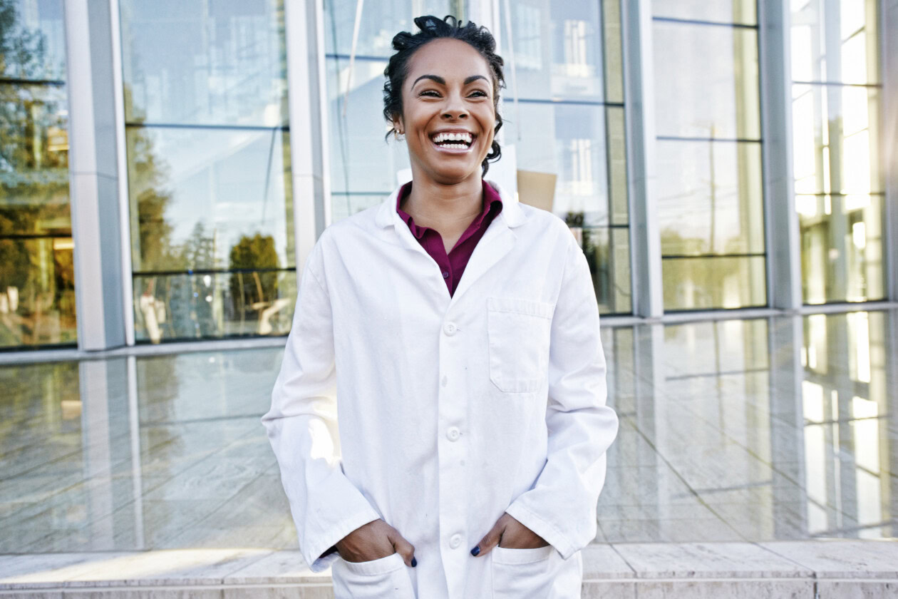 Portrait of laughing mixed race doctor outdoors at hospital