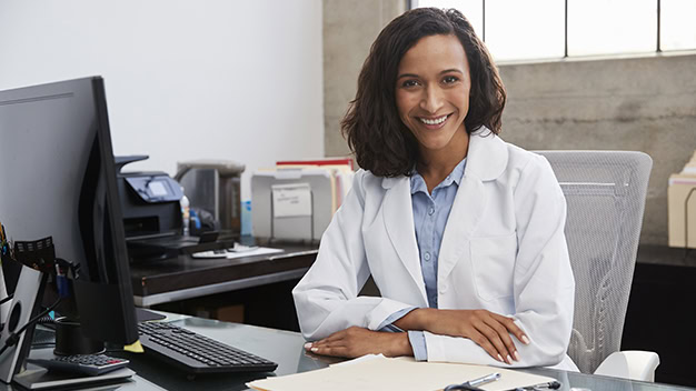 Young female doctor sitting at desk in an office, portrait
